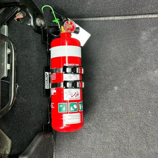 Close-up of a red fire extinguisher held in a KAP bracket at the base of the front seat in a RAM RAM 2500/3500