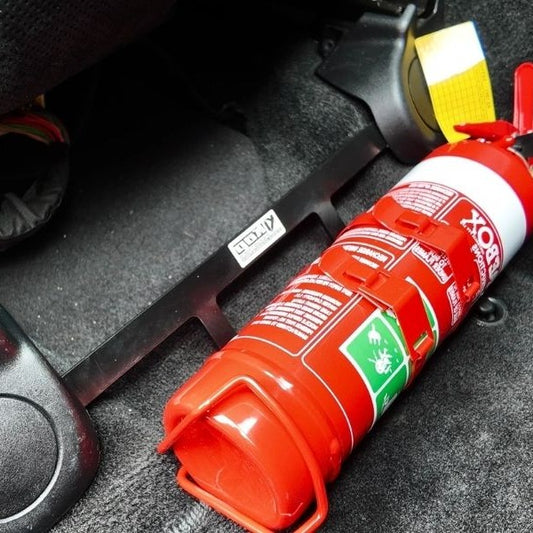Close-up of a red fire extinguisher held in a KAP bracket at the base of the front seat in a Jeep Grand Cherokee SRT8