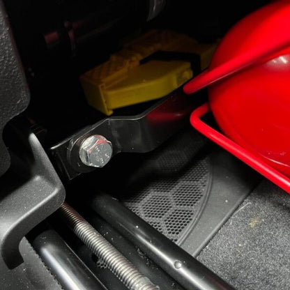 Close-up of a red fire extinguisher held in a KAP bracket at the base of the front seat in a BMW X3 M