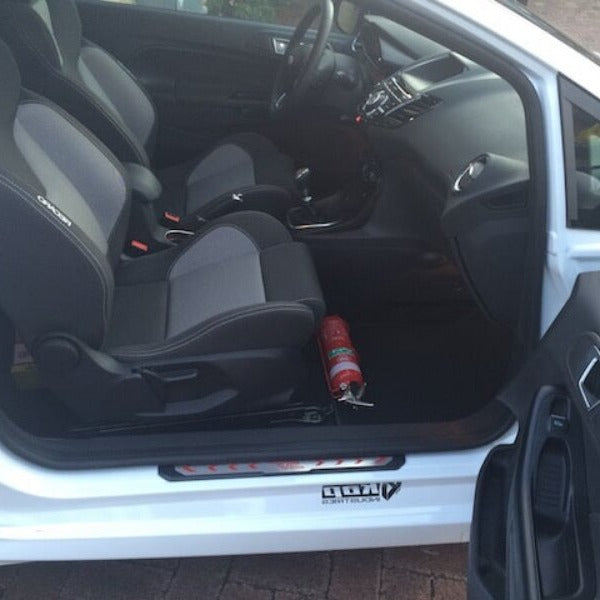 Ford Fiesta cabin with a red fire extinguisher mounted on a KAP bracket at the base of the front seat