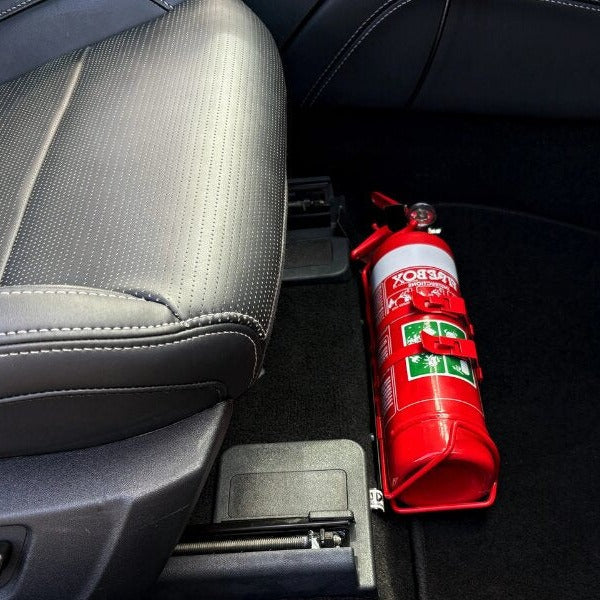 Close-up of a red fire extinguisher held in a KAP bracket at the base of the front seat in a Ford Mustang