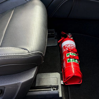 Close-up of a red fire extinguisher held in a KAP bracket at the base of the front seat in a Ford Mustang