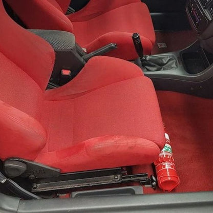 Close-up of a red fire extinguisher held in a KAP bracket at the base of the front seat in a Honda Integra