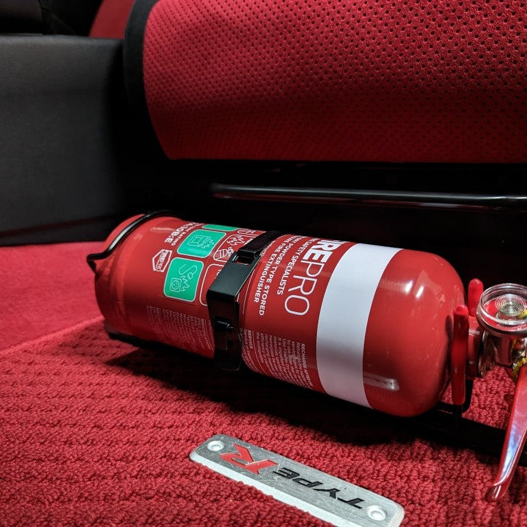 Close-up of a red fire extinguisher held in a KAP bracket at the base of the front seat in a Honda Civic Type R