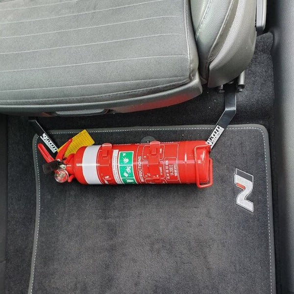 Close-up of a red fire extinguisher held in a KAP bracket at the base of the front seat in a Hyundai i30 N