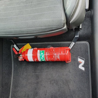 Close-up of a red fire extinguisher held in a KAP bracket at the base of the front seat in a Hyundai i30 N