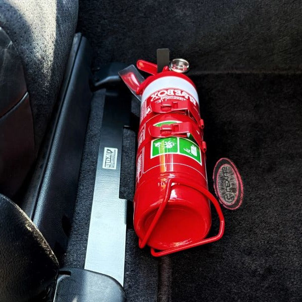 Close-up of a red fire extinguisher held in a KAP bracket at the base of the front seat in a Toyota Echo / Yaris