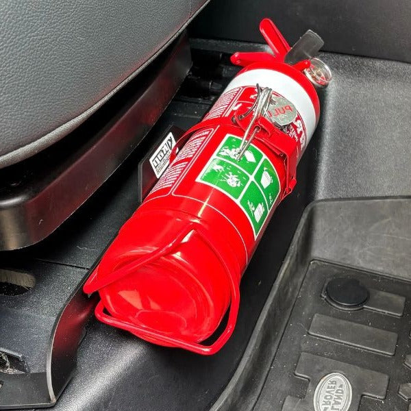 Close-up of a red fire extinguisher held in a KAP bracket at the base of the front seat in a Land Rover Discovery