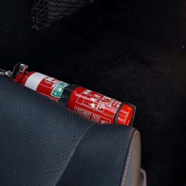 Close-up of a red fire extinguisher held in a KAP bracket at the base of the front seat in a Mercedes-Benz C63 AMG