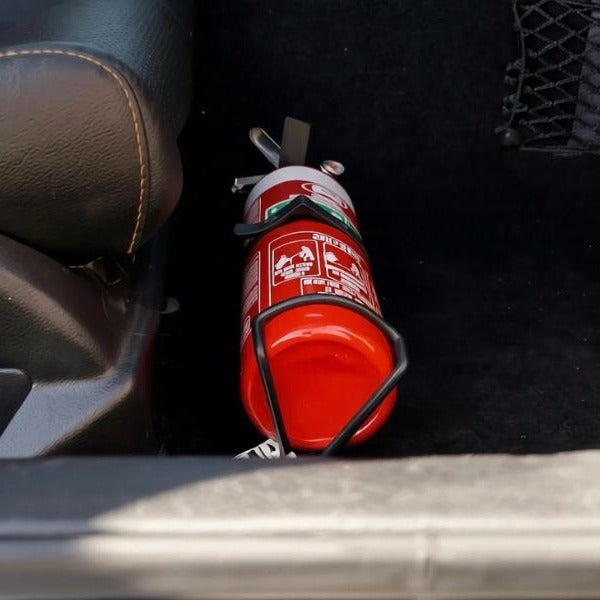 Close-up of a red fire extinguisher held in a KAP bracket at the base of the front seat in a Mercedes-Benz C63 AMG