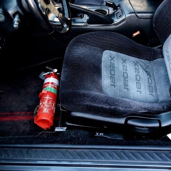 Nissan 240SX cabin with a red fire extinguisher mounted on a KAP bracket at the base of the right front seat