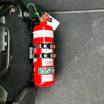 Close-up of a red fire extinguisher held in a KAP bracket at the base of the front seat in a RAM RAM 2500/3500