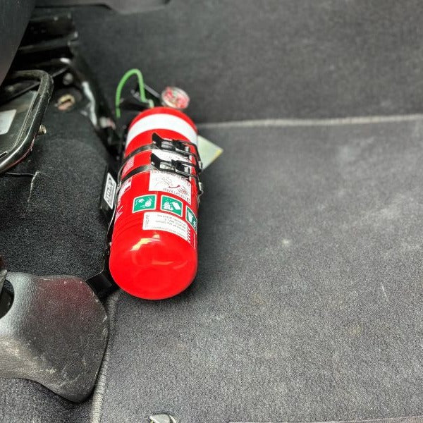 Close-up of a red fire extinguisher held in a KAP bracket at the base of the front seat in a RAM RAM 2500/3500