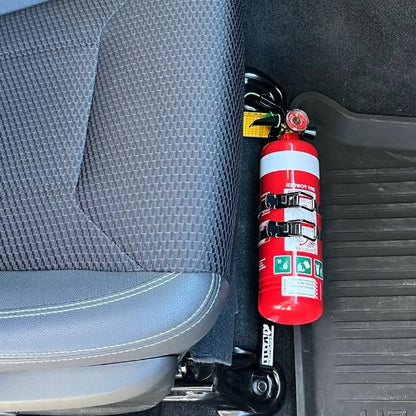 Close-up of a red fire extinguisher held in a KAP bracket at the base of the front seat in a Subaru WRX