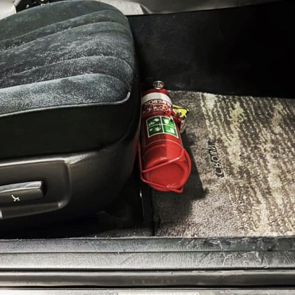 Close-up of a red fire extinguisher held in a KAP bracket at the base of the front seat in a Toyota Aristo / Lexus GS