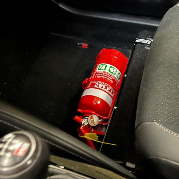 Close-up of a red fire extinguisher held in a KAP bracket at the base of the front seat in a Toyota C-HR