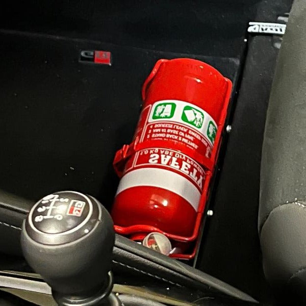 Close-up of a red fire extinguisher held in a KAP bracket at the base of the front seat in a Toyota C-HR
