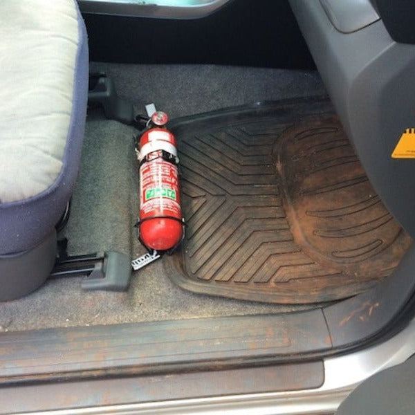 Close-up of a red fire extinguisher held in a KAP bracket at the base of the front seat in a Toyota FJ Cruiser