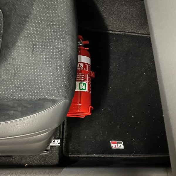 Close-up of a red fire extinguisher held in a KAP bracket at the base of the front seat in a Toyota Highlander