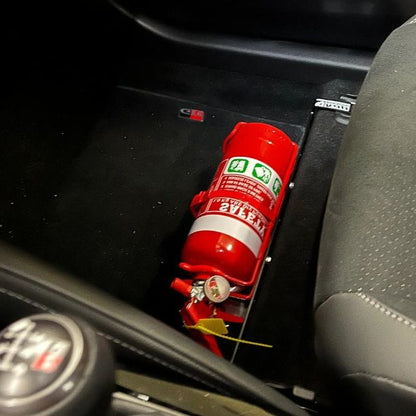 Close-up of a red fire extinguisher held in a KAP bracket at the base of the front seat in a Toyota Highlander
