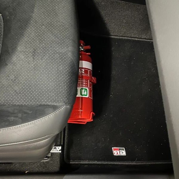 Close-up of a red fire extinguisher held in a KAP bracket at the base of the front seat in a Toyota Highlander