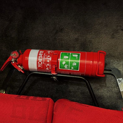 Close-up of a red fire extinguisher held in a KAP bracket at the base of the left front seat in a Toyota Soarer / Lexus SC
