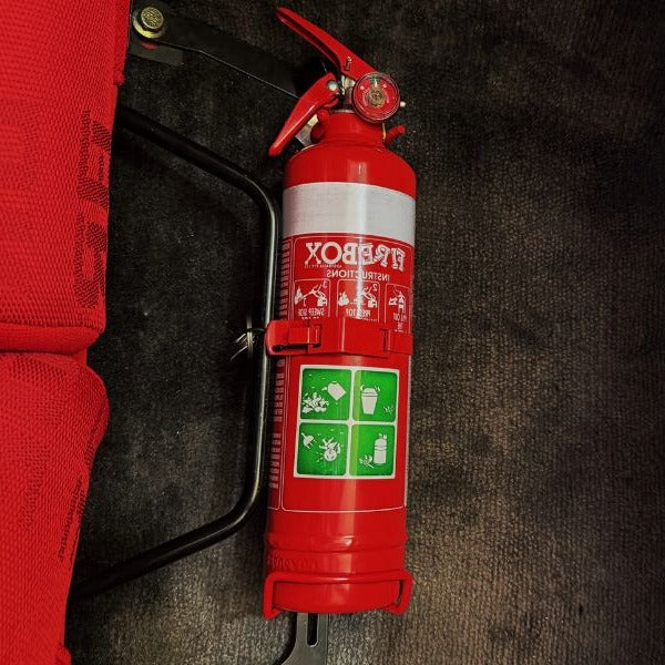 Close-up of a red fire extinguisher held in a KAP bracket at the base of the left front seat in a Toyota Soarer / Lexus SC
