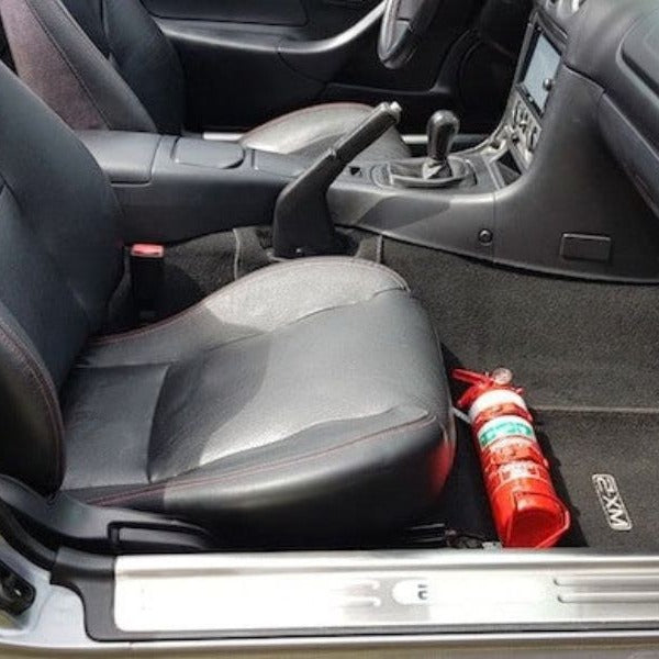 Mazda MX-5 Miata cabin with a red fire extinguisher mounted on a KAP bracket at the base of the right front seat