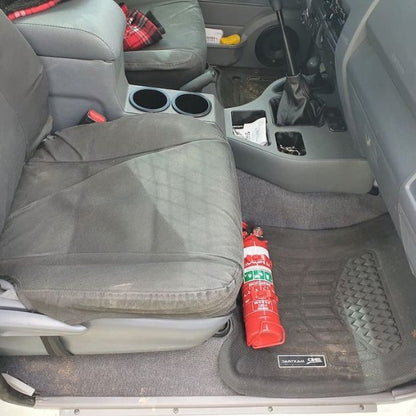 Toyota LandCruiser 80 Series cabin with a red fire extinguisher mounted on a KAP bracket at the base of the left front seat