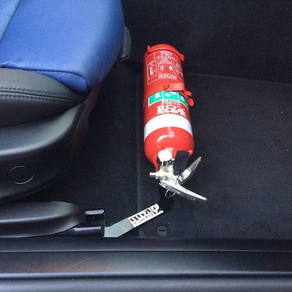 Close-up of a red fire extinguisher held in a KAP bracket at the base of the front seat in a BMW Z4 / Z4 M