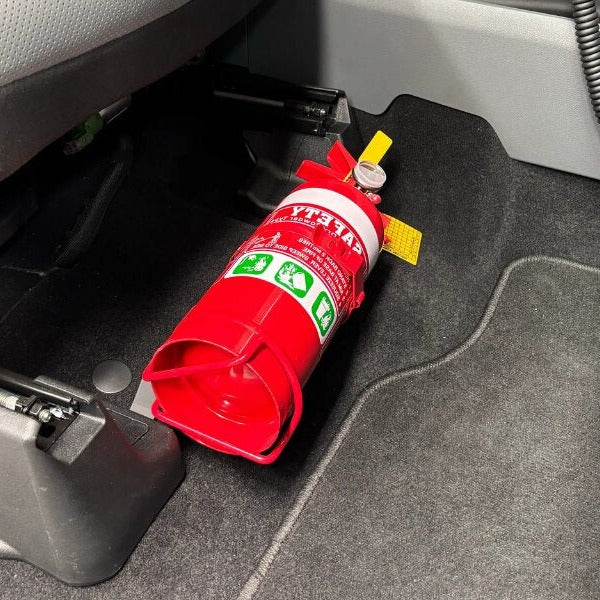 Close-up of a red fire extinguisher held in a KAP bracket at the base of the front seat in a Ford F-150
