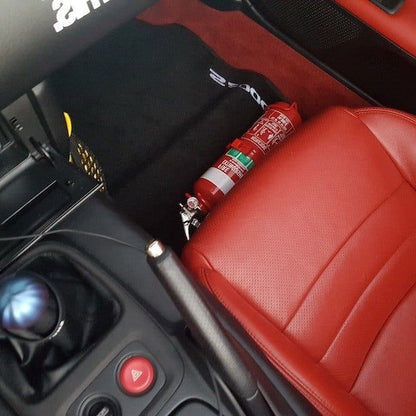 Close-up of a red fire extinguisher held in a KAP bracket at the base of the left front seat in a Honda S2000