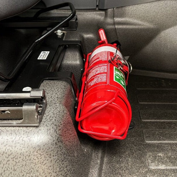 Close-up of a red fire extinguisher held in a KAP bracket at the base of the front seat in a Ineos Quartermaster