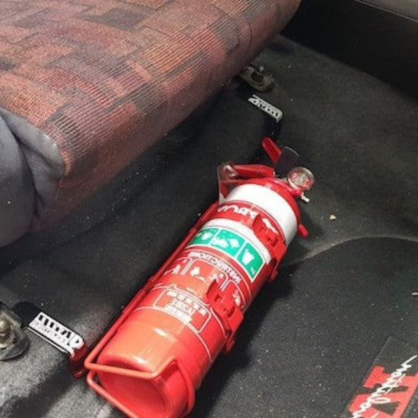 Close-up of a extinguisher held in a KAP bracket at the base of the left front seat in a Mitsubishi Lancer Evolution VI