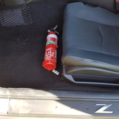 Nissan 350Z cabin with a red fire extinguisher mounted on a KAP bracket at the base of the left front seat