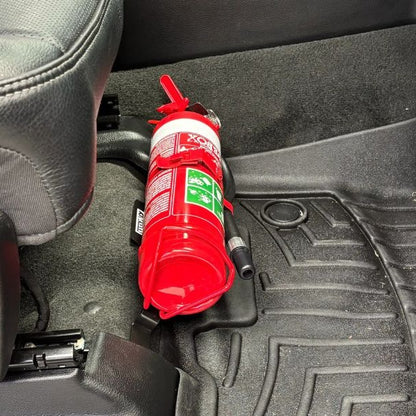 Close-up of a red fire extinguisher held in a KAP bracket at the base of the front seat in a RAM 1500