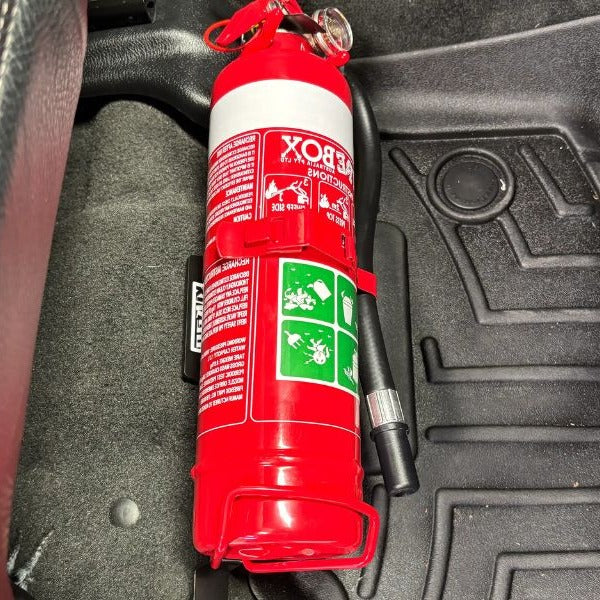 Close-up of a red fire extinguisher held in a KAP bracket at the base of the front seat in a RAM 1500