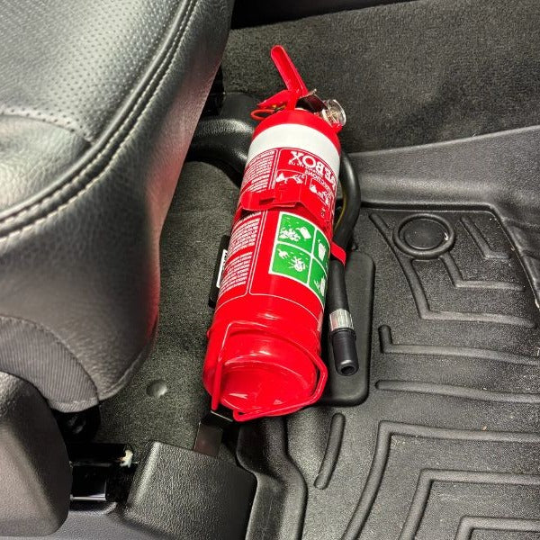 Close-up of a red fire extinguisher held in a KAP bracket at the base of the front seat in a RAM 1500