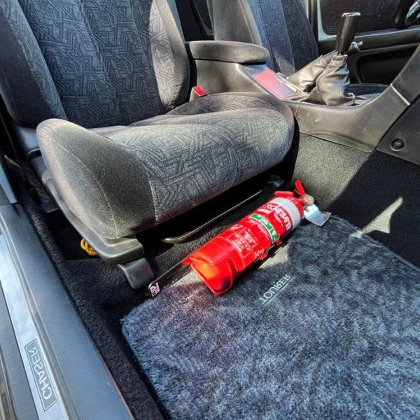 Toyota Chaser/Cresta/Mark II cabin with a red fire extinguisher mounted on a KAP bracket at the base of the left front seat
