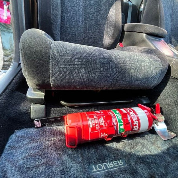Close-up of a extinguisher held in a KAP bracket at the base of the left front seat in a Toyota Chaser/Cresta/Mark II