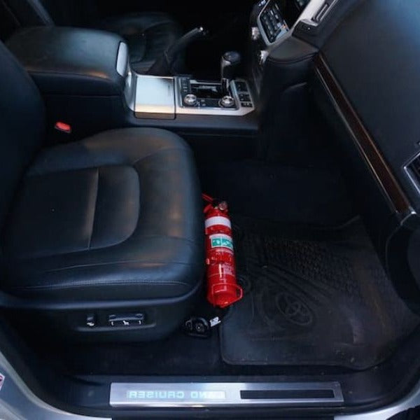Toyota LandCruiser 200 Series cabin with a red fire extinguisher mounted on a KAP bracket at the base of the front seat