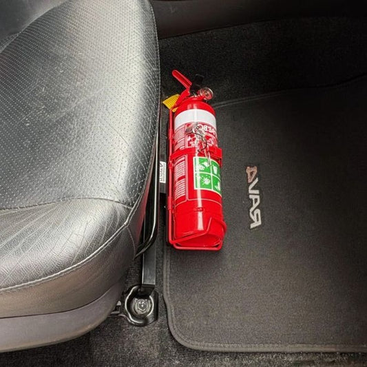 Close-up of a red fire extinguisher held in a KAP bracket at the base of the front seat in a Toyota RAV4