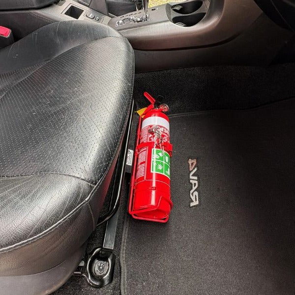 Close-up of a red fire extinguisher held in a KAP bracket at the base of the front seat in a Toyota RAV4