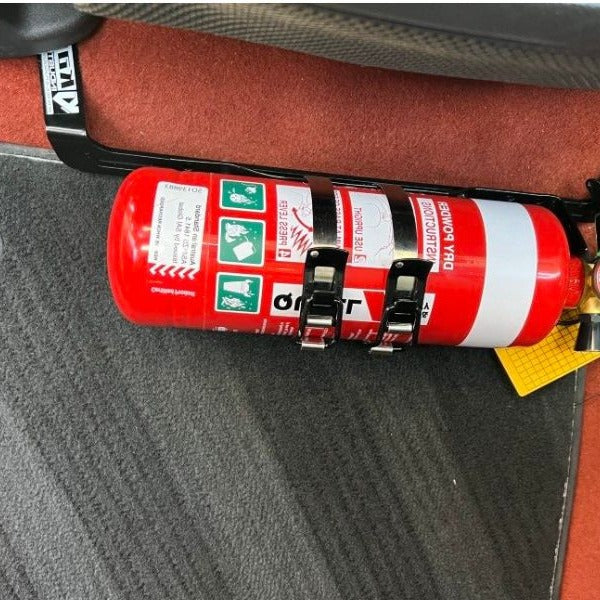 Close-up of a red fire extinguisher held in a KAP bracket at the base of the front seat in a Volvo C30