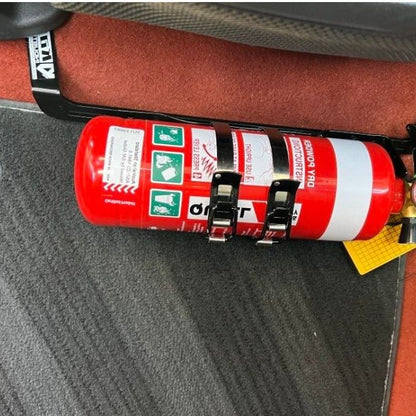 Close-up of a red fire extinguisher held in a KAP bracket at the base of the front seat in a Volvo C30