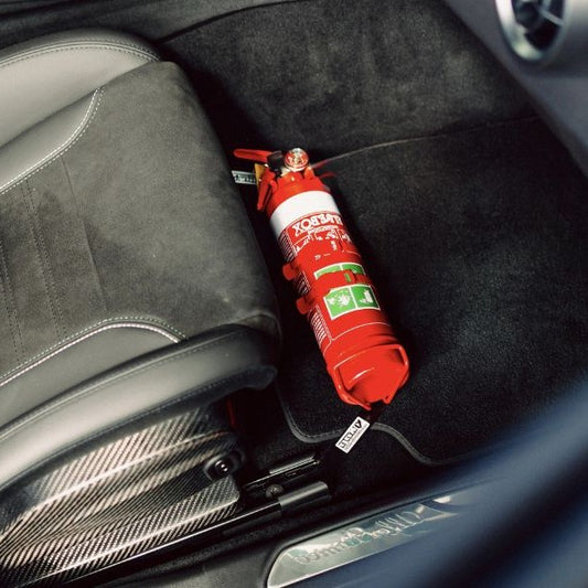 Close-up of a red fire extinguisher held in a KAP bracket at the base of the front seat in a Alfa Romeo Giulia