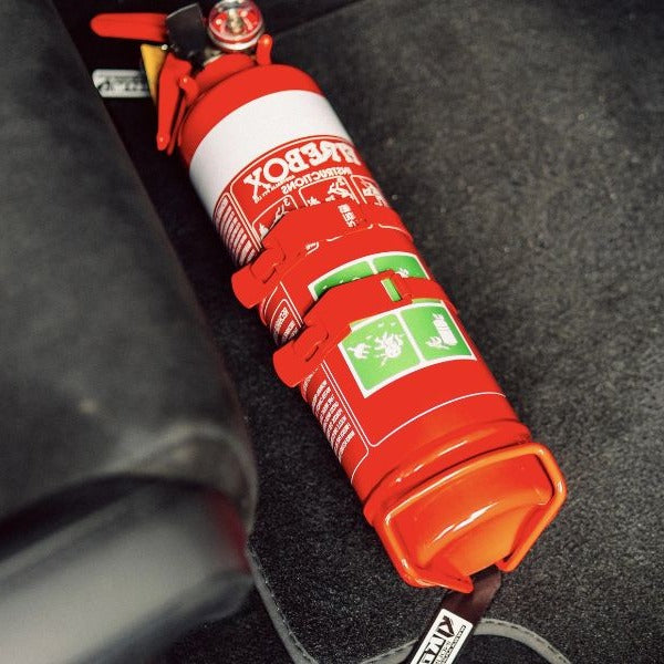 Close-up of a red fire extinguisher held in a KAP bracket at the base of the front seat in a Alfa Romeo Giulia