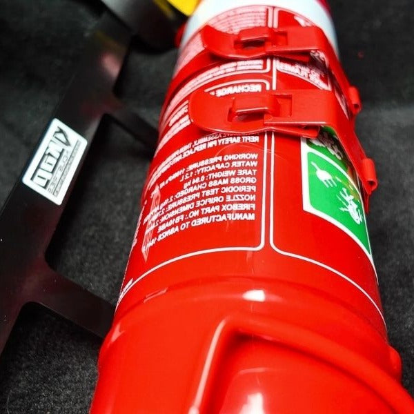 Close-up of a red fire extinguisher held in a KAP bracket at the base of the front seat in a Jeep Grand Cherokee SRT8
