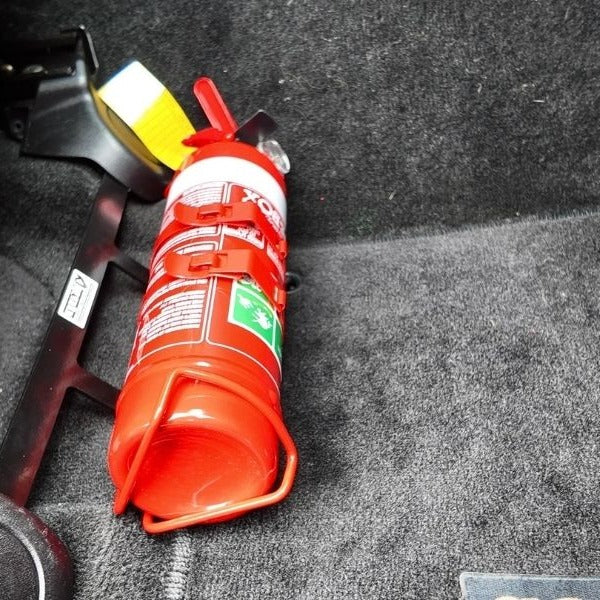 Close-up of a red fire extinguisher held in a KAP bracket at the base of the front seat in a Jeep Grand Cherokee SRT8
